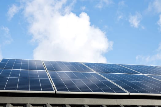 Aerial view of solar panel stand-alone photovoltaic plant system on cloudy blue sky background. Clean alternative energy power in nature concept, sustainable resources. Professional installation
