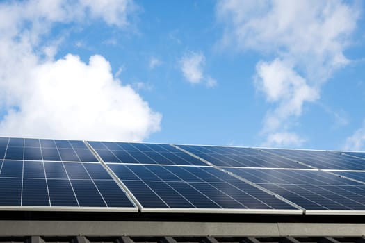 Aerial view of solar panel cells against cloudy blue sky. Alternative energy concept, sustainable resources. House with solar panels stand-alone photovoltaic plant system. Professional installation
