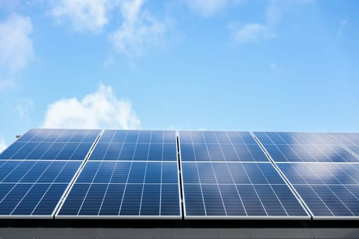 Solar panel cells on cloudy blue sky background. Clean alternative energy power concept. Modern house with solar panels stand-alone photovoltaic plant system on metal sheet roof. Go green