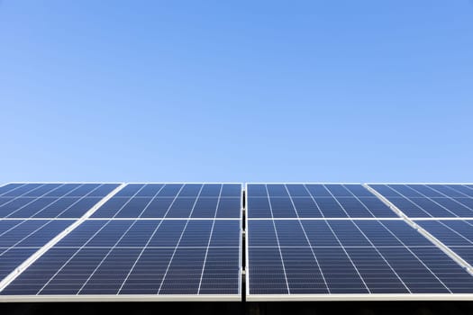 Aerial view of solar panel cells on clear blue sky background. Alternative energy concept. Modern house with solar panels stand-alone photovoltaic plant system on household metal sheet roof