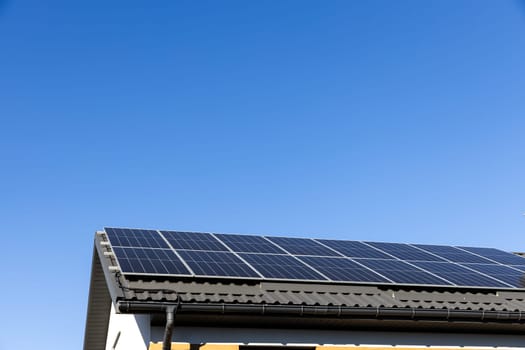 Clean alternative energy power in nature concept, sustainable resources. Modern house with solar panel stand-alone photovoltaic plant system on household metal sheet rooftop. Professional installation