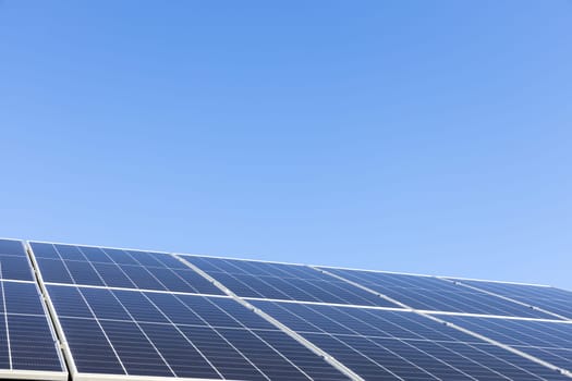 Modern house with solar panels stand-alone photovoltaic plant system on household metal sheet roof. Clear blue sky background. Clean alternative energy power concept, sustainable resources