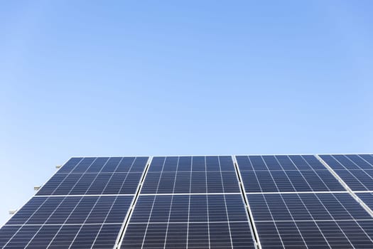 Aerial view of solar panel cells on clear blue sky background. Alternative energy concept. Modern house with solar panels stand-alone photovoltaic plant system on household metal sheet roof