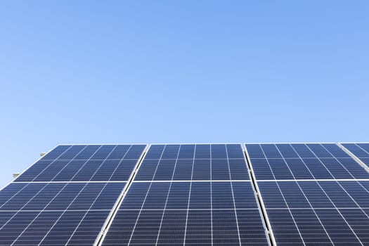 Aerial view of solar panel cells on clear blue sky background. Alternative energy concept. Modern house with solar panels stand-alone photovoltaic plant system on household metal sheet roof