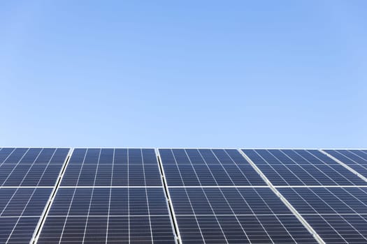Aerial view of solar panel cells on clear blue sky background. Clean alternative energy power concept, sustainable resources. Modern house, solar panels stand-alone photovoltaic plant system on roof