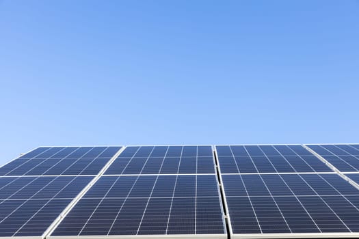 Aerial view of solar panel cells on clear blue sky background. Alternative energy concept. Modern house with solar panels stand-alone photovoltaic plant system on household metal sheet roof