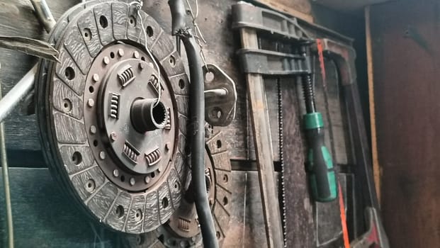A cluttered workshop scene showcasing an assortment of tools hanging on a wooden wall and surrounding shelves, creating a rustic and industrial atmosphere.