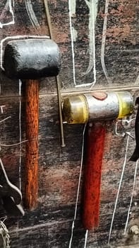 A cluttered workshop scene showcasing an assortment of tools hanging on a wooden wall and surrounding shelves, creating a rustic and industrial atmosphere.
