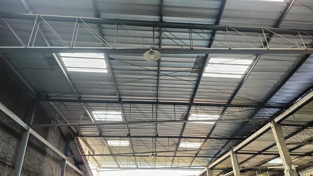 View of a sturdy metal roof with beams inside a spacious warehouse. The structure depicts industrial architecture, showcasing strength and functionality. This space is ideal for storage and manufacturing.