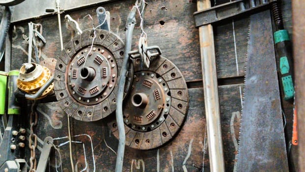 A cluttered workshop scene showcasing an assortment of tools hanging on a wooden wall and surrounding shelves, creating a rustic and industrial atmosphere.