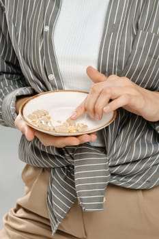 Unrecognizable woman counting pills or vitamins scattered on a plate