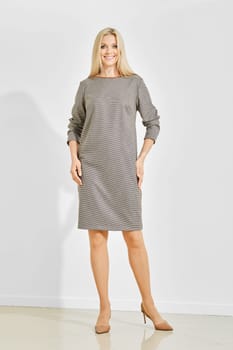 Fashionable elegant woman wearing a knee-length houndstooth dress and brown heels