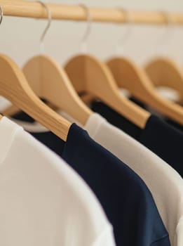 A collection of neatly hung shirts on wooden hangers showcases simple clothing in a well-lit indoor space.