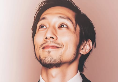 A man in a suit gazes happily upwards, with a gentle smile and relaxed demeanor, conveying a sense of positivity and hope.
