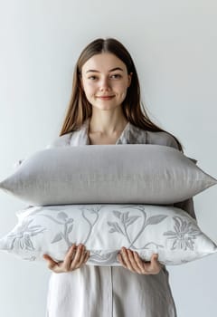 A young woman smiles while holding two decorative pillows in a bright indoor space, showcasing stylish home decor.