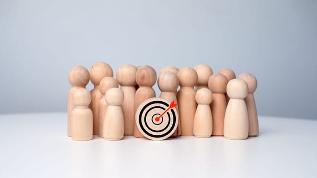 Wooden dolls standing around dart board for creating and targeting business objectives. Target concept of business and personnel in a company. Marketing solutions, targets for business investment.