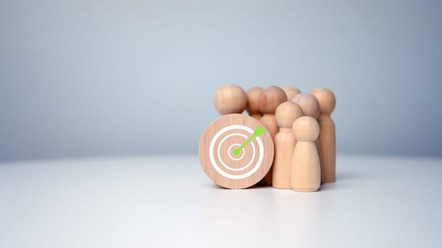 Wooden dolls standing around dart board for creating and targeting business objectives. Target concept of business and personnel in a company. Marketing solutions, targets for business investment.