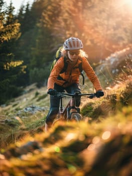 A cyclist in an orange jacket rides a mountain bike on a grassy trail, the sun casting a warm glow over the forested landscape