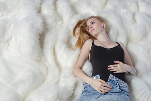 Blonde pregnant young woman. is lying on organic wool blanket. Horizontally.