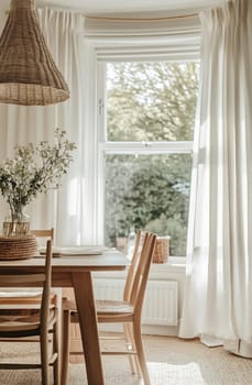 A cozy dining space filled with natural light from a large window, adorned with fresh flowers and simple decor elements.