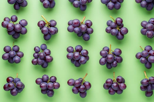 Vibrant bunches of dark grapes arranged neatly on a bright green surface create a striking visual display.
