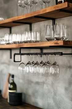 Glasses are neatly arranged on wooden shelves, showcasing a stylish kitchen design with metal accents and a warm atmosphere.