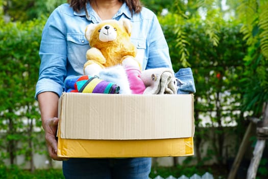 Volunteer collect cloth and doll in cardboard box to donate.