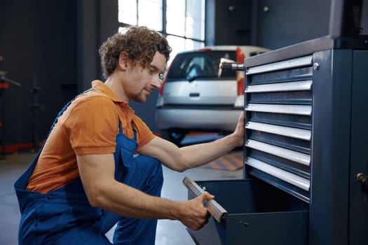 Male mechanic taking tools for work. Professional repairman service at auto garage