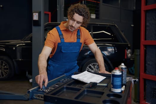 Male mechanic taking tools for work. Professional repairman service at auto garage