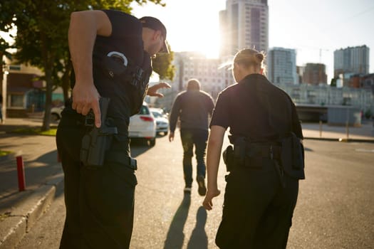 Patrol officers preparing weapon while chasing offender on urban street. Police force working on crime prevention and punishment of violator