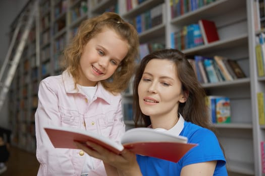 Portrait of happy curious mother and daughter reading book while enjoying shopping time at bookstore