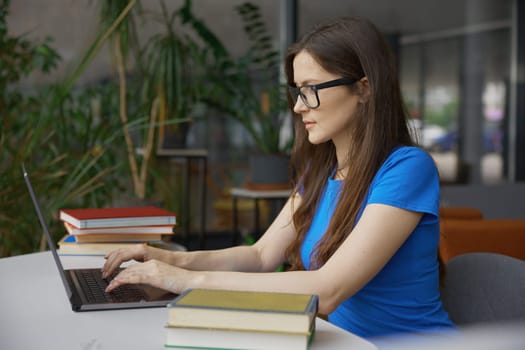 Young woman student studying or doing online research on internet using laptop computer in library