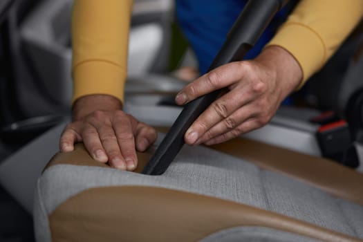 Closeup of vacuuming car interior from dust using professional equipment. Car-wash service concept
