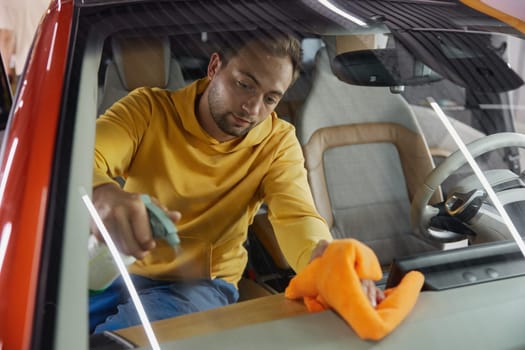 Service master working at car wash service providing professional safety leather dirt cleansing and treatment procedure