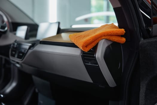 Clean rag towel on car dashboard for cleansing, polishing, hygienic treatment and detailing plastic parts in auto service