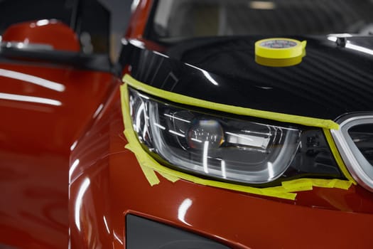 Closeup view on car headlights with attached masking tape. Preparation for cleansing and polishing headlamp process in automotive wash service