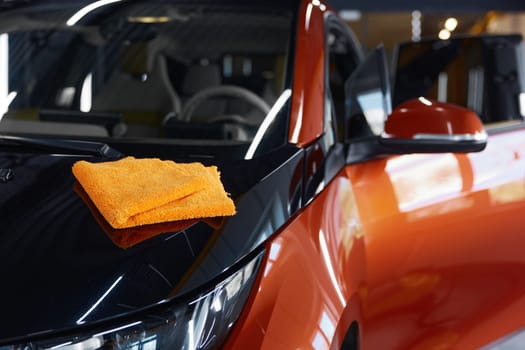 Microfiber towel cloth on shiny glossy surface of polished car. Professional auto service providing high quality cleansing routine procedure for luxury automobile
