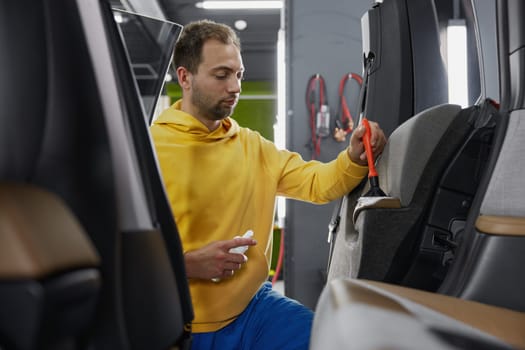 Male master working at car wash service providing professional safety leather dirt cleansing and treatment procedure