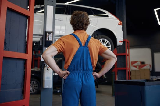 Professional male auto mechanic in uniform in confidence posing at car repair workshop
