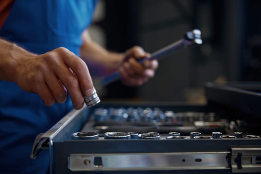 Crop shot of tool box and male mechanic hands taking wrench for work. Professional repairman service at auto garage