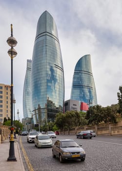 Baku, Azerbaijan - May 6, 2024: The iconic Flame Towers rise majestically amidst a lively Baku street scene, reflecting the dynamic energy of the city on a cloudy day