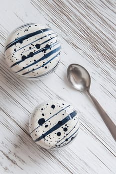 Two elegant dessert bowls with navy blue designs sit beside a silver spoon on a rustic wooden table.