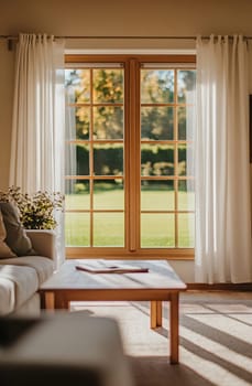 A cozy living room features a large window with sheer curtains, offering a view of the vibrant green garden outside.