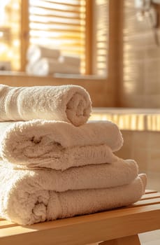 Plush towels are beautifully arranged on a wooden bench in a sunlit, inviting bathroom setting, enhancing relaxation and comfort.