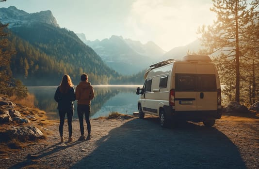 A couple stands by a serene lake, gazing at the sunset while a camper van is parked nearby in a tranquil mountain setting.