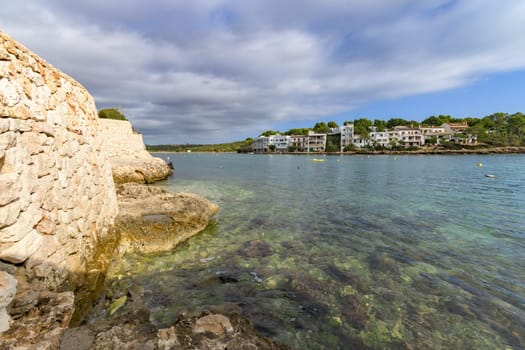 Peaceful coastal scene with rocky shore and clear water under a cloudy sky, porto petro, mallorca balearic islands, spain