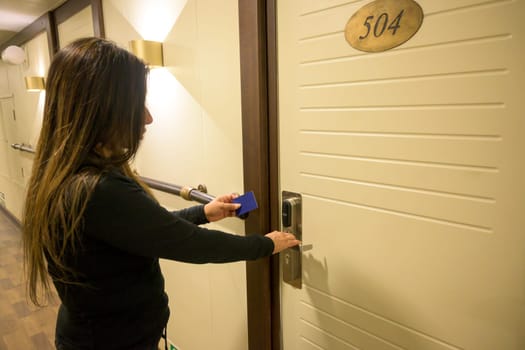 Latin Woman using a keycard to unlock a door in a hallway, key electronic lock, hotel room, holidays in mallorca, spain.