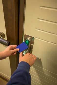 Close-up of a hand using a blue card key on a hotel door lock, key electronic lock, hotel room, holidays in mallorca, spain.