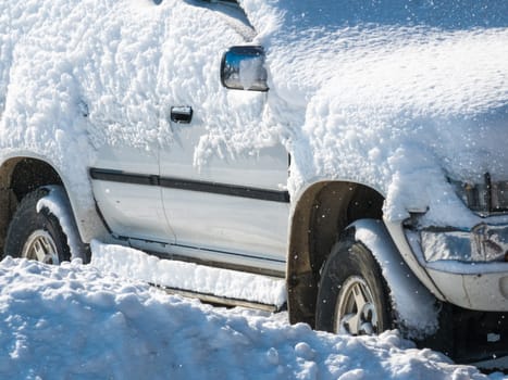 snow covered old white SUV car at sunny white winter day