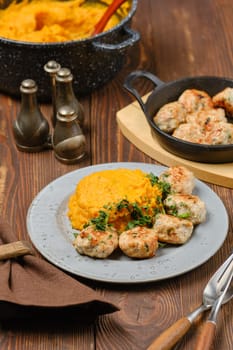 Homemade chicken meatballs garnished with herbs sit beside a generous serving of creamy mashed pumpkin